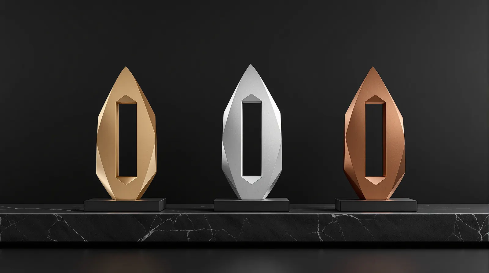 Three websbz award sculptures in gold, platinum and copper on a black stone shelf